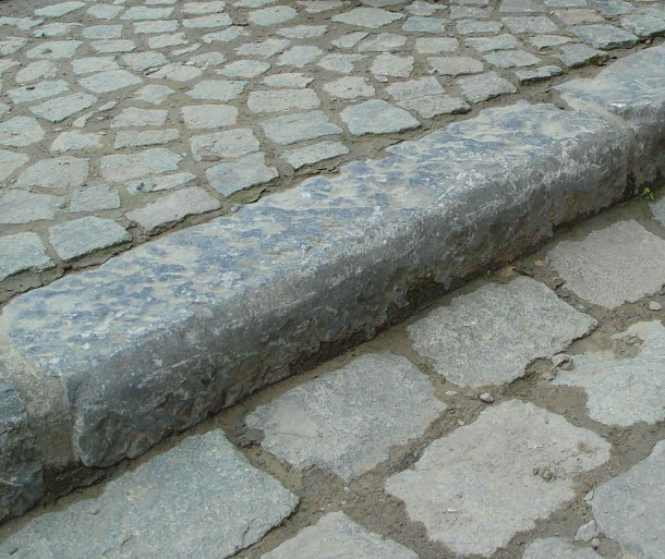 在大量使用混凝土作为标准材料之前，路沿是由当地采石或其他开采的石材制成的。如上所示，花岗岩是一种很好的(尽管昂贵)材料，因为其硬化性质降低了其对街道活动(如马车交通、非充气车轮、行人)侵蚀和损坏的总体敏感性。它的重量和密度也比柔软的石头有优势，因为它形成了坚硬的边缘，易于清洁，不易移动或偷窃。照片rackcdn.com